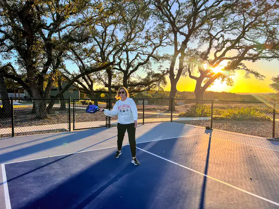 Guest playing pickleball at sunset under the live oaks