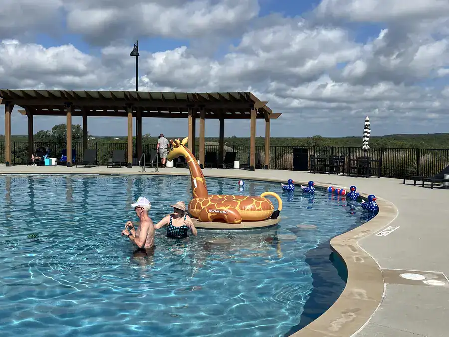 Guests floating in the resort pool with the pergola and Hill Country ridge behind