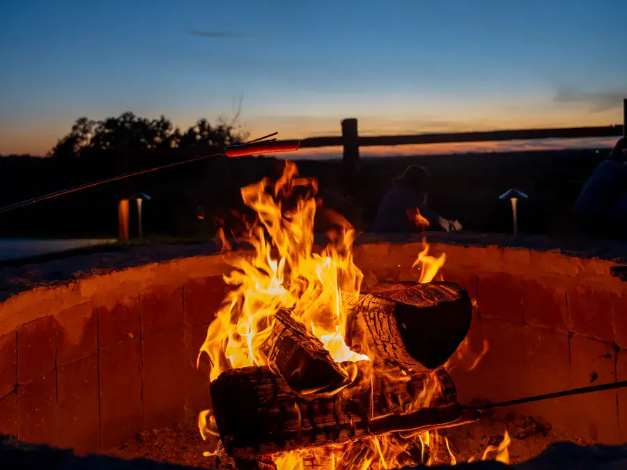 Wood fire burning in a stone community fire pit at dusk