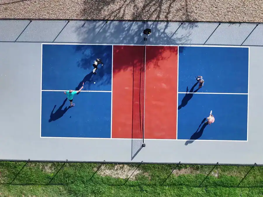 Overhead view of a doubles pickleball game on a red and blue court