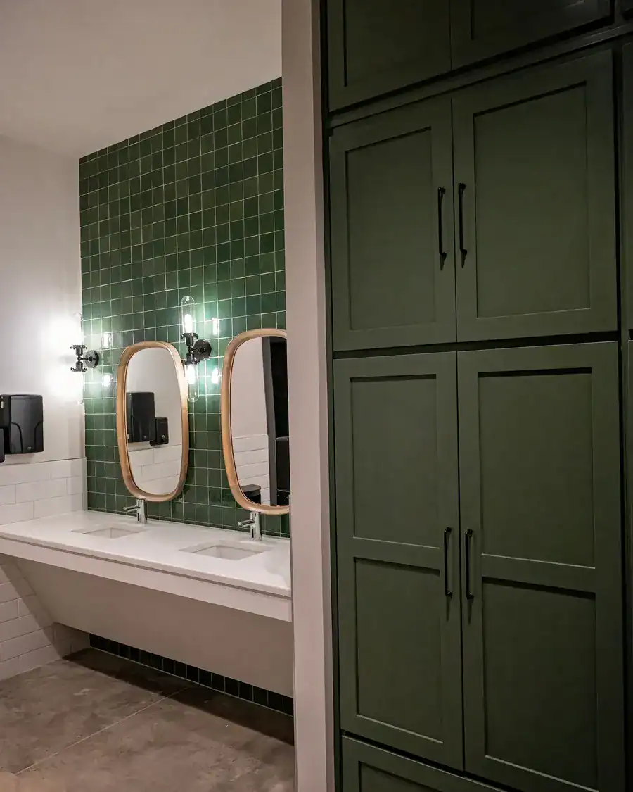 Amenity center restroom with green tile and round wood mirrors