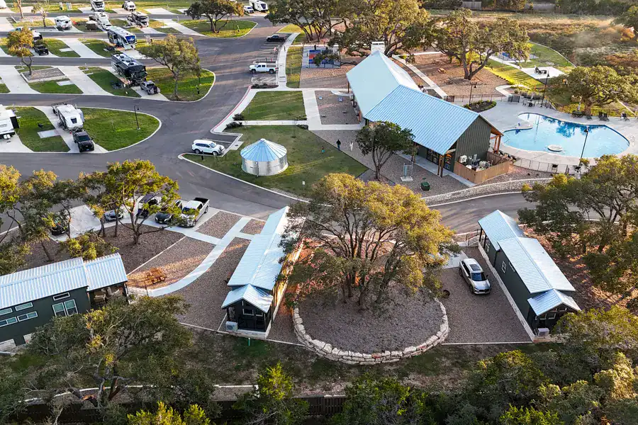 Aerial view of the three cabins among oaks, with the clubhouse and pool just beyond
