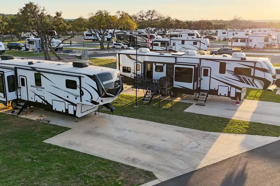 Fifth-wheel RVs settled on back-in sites under live oaks