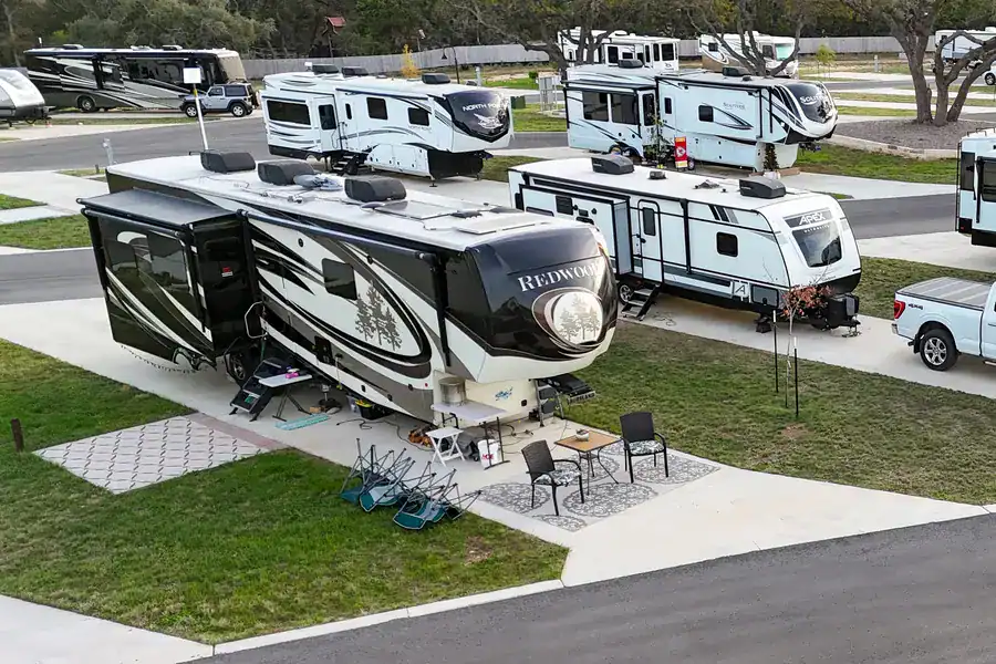 Fifth-wheel RV set up with a patio table and chairs on a concrete full-hookup site