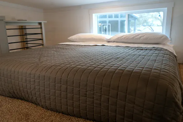 King bed with a grey quilt in The Mingo sleeping loft