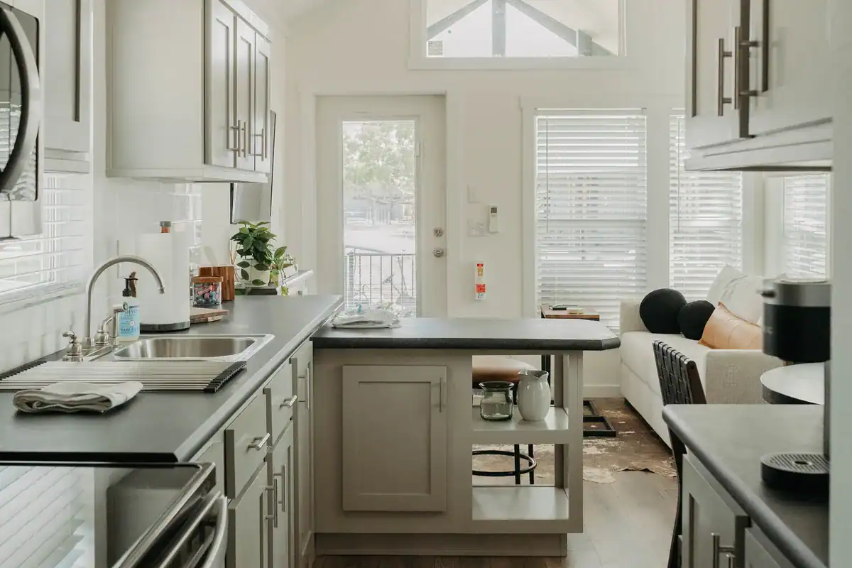 The Mingo's grey painted kitchen with dark counters, looking toward the glass door and gable window