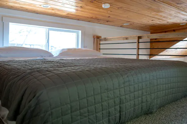 King bed in the Sea Biscuit sleeping loft under a knotty-pine ceiling