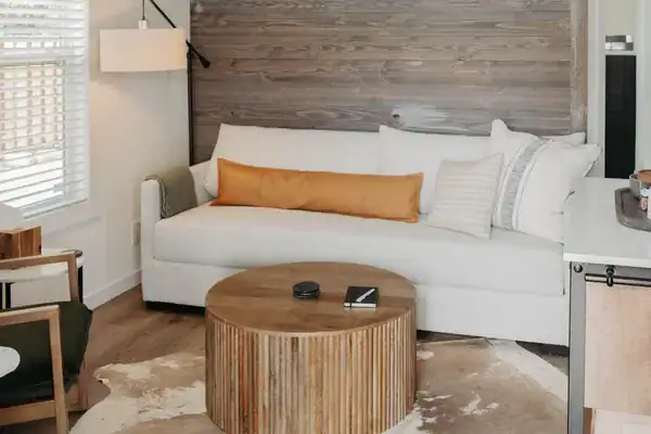 Secretariat living room with a barnwood accent wall, white sofa and round slatted coffee table