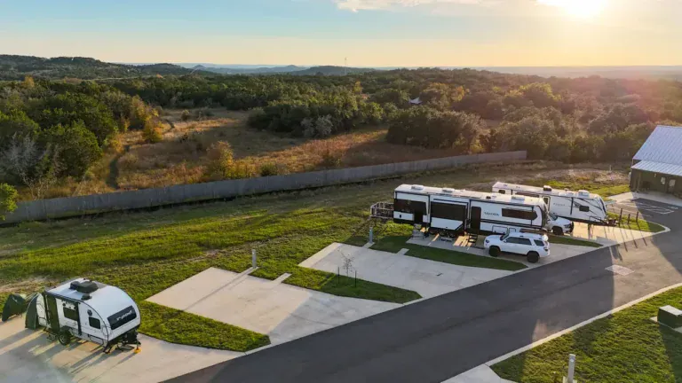 Golden-hour aerial of back-in RV sites at Horseshoe Ridge with the Texas Hill Country behind