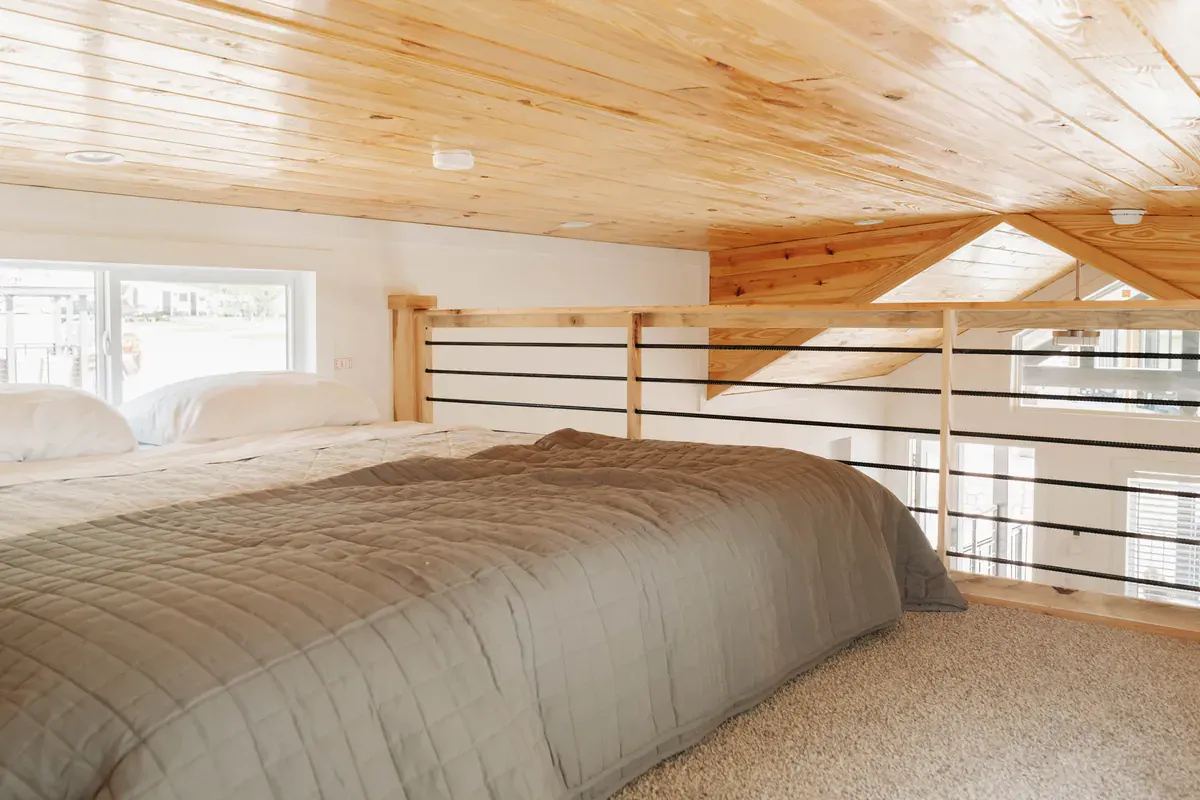 King bed in the Sea Biscuit sleeping loft under a knotty-pine ceiling