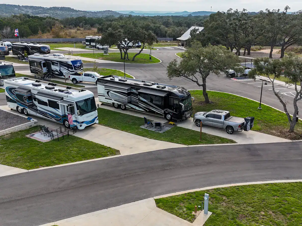 Two Class A motorhomes parked on long concrete sites at Horseshoe Ridge in Wimberley, Texas