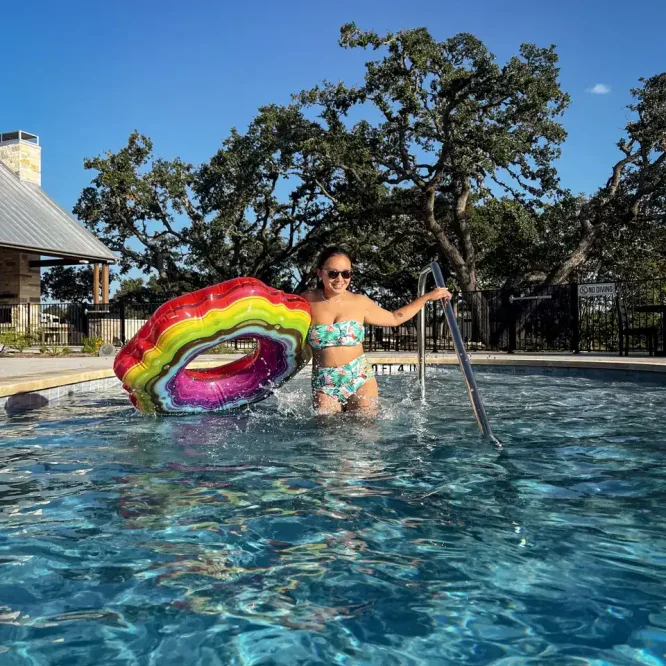 Woman in a swimsuit with rainbow float in a pool at Horseshoe Ridge RV.