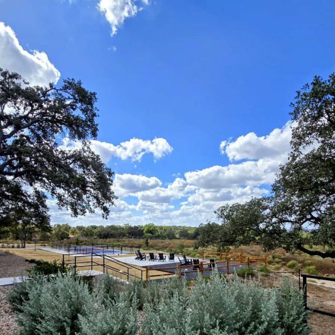 Scenic view of Horseshoe Ridge RV with outdoor seating and lush greenery under a blue sky.