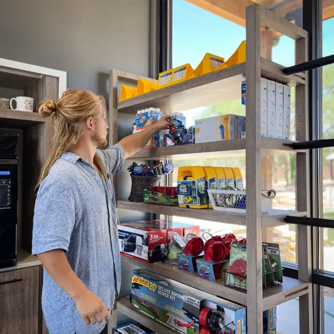 Person organizing tools on a metal shelf near a large window at Horseshoe Ridge RV.