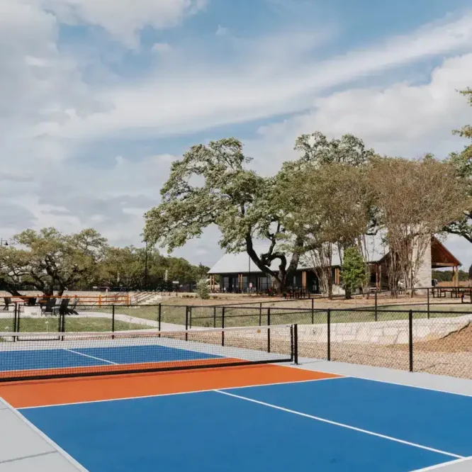 Tennis courts at Horseshoe Ridge RV with trees and a building in the background.