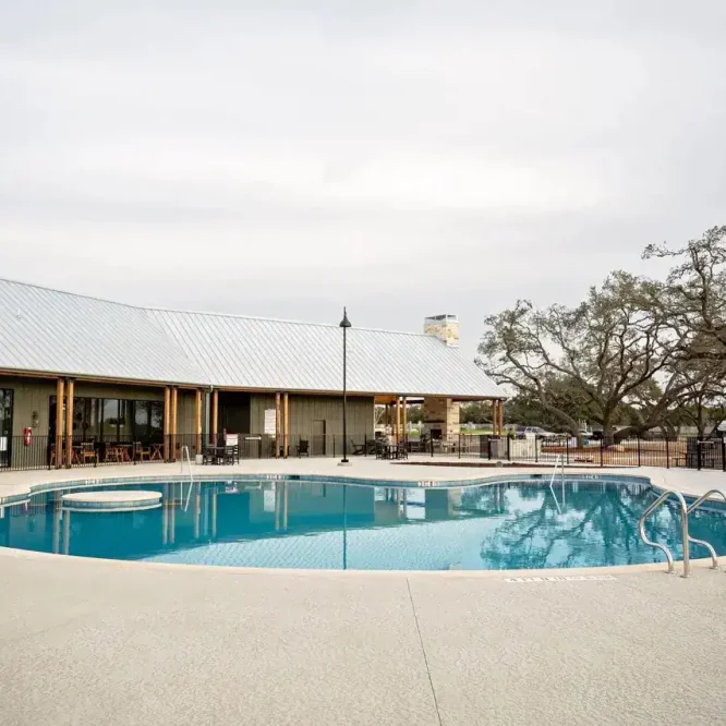 Outdoor swimming pool at Horseshoe Ridge RV resort with surrounding trees and building.