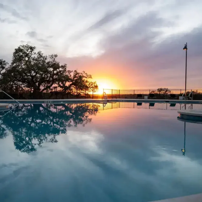 Scenic sunset over the Horseshoe Ridge RV pool with calm water reflection.