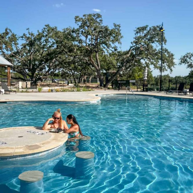 Relaxing pool scene at Horseshoe Ridge RV with two women enjoying the water.