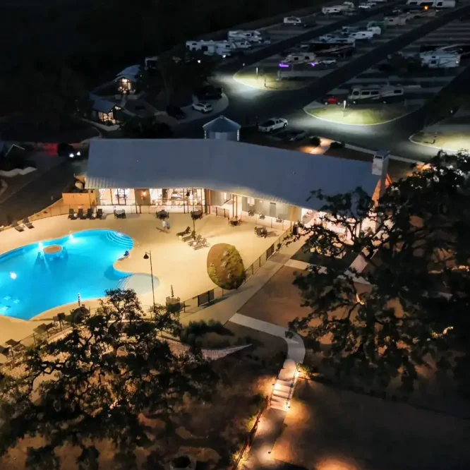 Night view of Horseshoe Ridge RV park with illuminated pool and RVs.